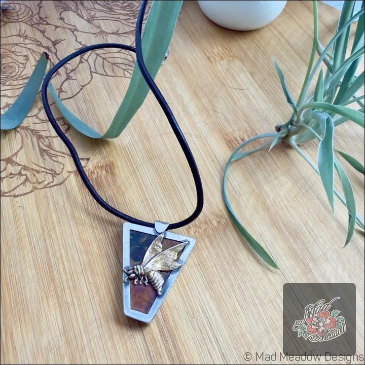 Unleash your inner queen with our stunning Queen Bee Sterling Silver Pendant Necklace! 🌼✨ This beautiful piece is more than just jewelry; it’s a statement of empowerment! 

🌟 Features:
- Sterling Silver & Brass charm 🐝
- Mookaite Jasper for strength 🌈
- 18" leather cord with sister hook clasp 🖤
- Open back design for earthly energy 🌍

Grab this unique beauty for just $155.00 and embrace your journey of growth and leadership. But hurry, the offer ends soon! 

Shop now: https://ssdlr.shop/l/6c71dae2 
#Empowerment #BeeInspired #JasperJewelry #MadMeadowDesigns #QueenBee