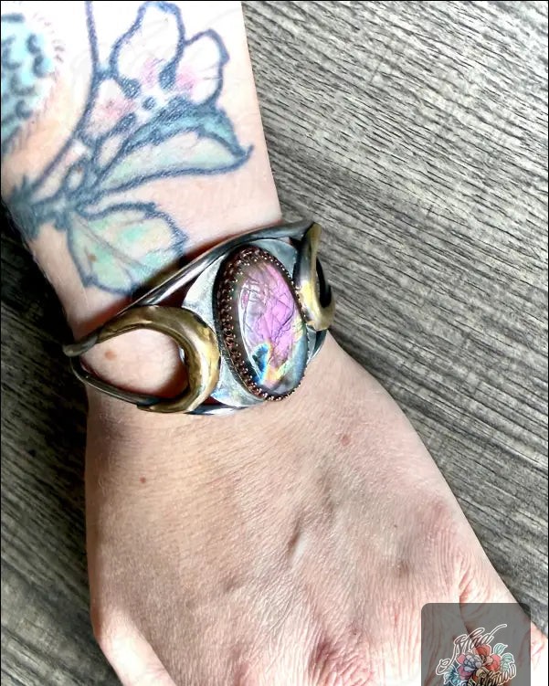 Who says you can’t wear your magic? ✨

This Purple Labradorite Bold Mystical Sterling Silver Cuff isn’t just jewelry; it’s a statement of your inner power. 

With its stunning oval labradorite stone and enchanting crescent moons, it’s designed to spark intuition and ward off negativity. 

Style meets spirituality! 

Wear it proudly and let the world see your unique vibe. 

Now at $290.00. Snag this one-of-a-kind piece today! 
👉 

#HandcraftedJewelry #BohoStyle #CosmicVibes #WitchyFashion #LabradoriteMagic