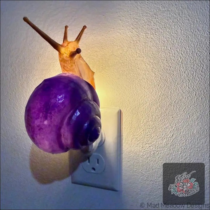 Is your space in need of a sprinkle of magic? 🌙✨ 

Meet our Charming Snail Night Light, where whimsy meets functionality! 

With vibrant purple and golden yellow hues, this oversized wall-mounted beauty isn't just a light—it's a work of art that transforms bedrooms, nurseries, or creative spaces into enchanting wonderlands. 

Soft ambient glow? Check. Quirky décor piece? Absolutely. 

This delightful snail will not only brighten your evenings but also spark joy-filled conversations. 

Bring home this enchanting piece now at $40.00: 

#HomeDecor #WhimsicalDesign #NightLight #BohoStyle #MadMeadowDesigns