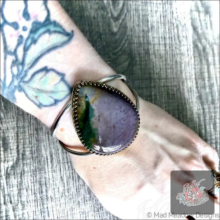 Prepare to turn heads with the Purple Jasper Bold Boho Sterling Silver Cuff Bracelet! 💜✨ 

This stunning piece isn’t just jewelry; it’s a statement of style and intention. Handcrafted from sterling silver and adorned with a mesmerizing purple Jasper gemstone, it brings a touch of mystical charm to any outfit.

Feel the calm wash over you as this beauty inspires spiritual awareness and inner peace. 

Perfectly adjustable, it fits small to medium wrists, ensuring a comfortable wear all day long.

Now at $240.00 
 

#BohoChic #ArtisanJewelry #MysticalStyle #JasperJewels #MadMeadowDesigns